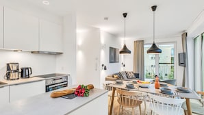 A modern kitchen with a built-in oven, a coffee maker, and a dining area with a table and chairs.