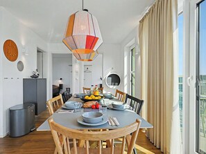 A dining area with a round table, chairs, a hanging pendant light, and a view of the outdoors. - Penthouse Imort (654) by Interhome (Lembruch)