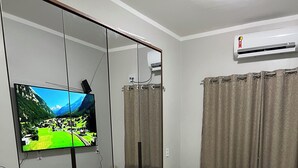 Een slaapkamer met een bed, een televisie, een airconditioner en een bureau.
