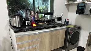Een keuken met een ingebouwde wasmachine, een koffiezetapparaat en een blender op het aanrecht.