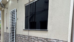 Een gebouw met een groot raam, een metalen hekwerk en een betegelde muur.