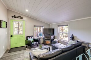 Ein Wohnzimmer mit Kamin, Fernseher und einer grünen Tür, mit einem Schild, auf dem 'adventure' steht.