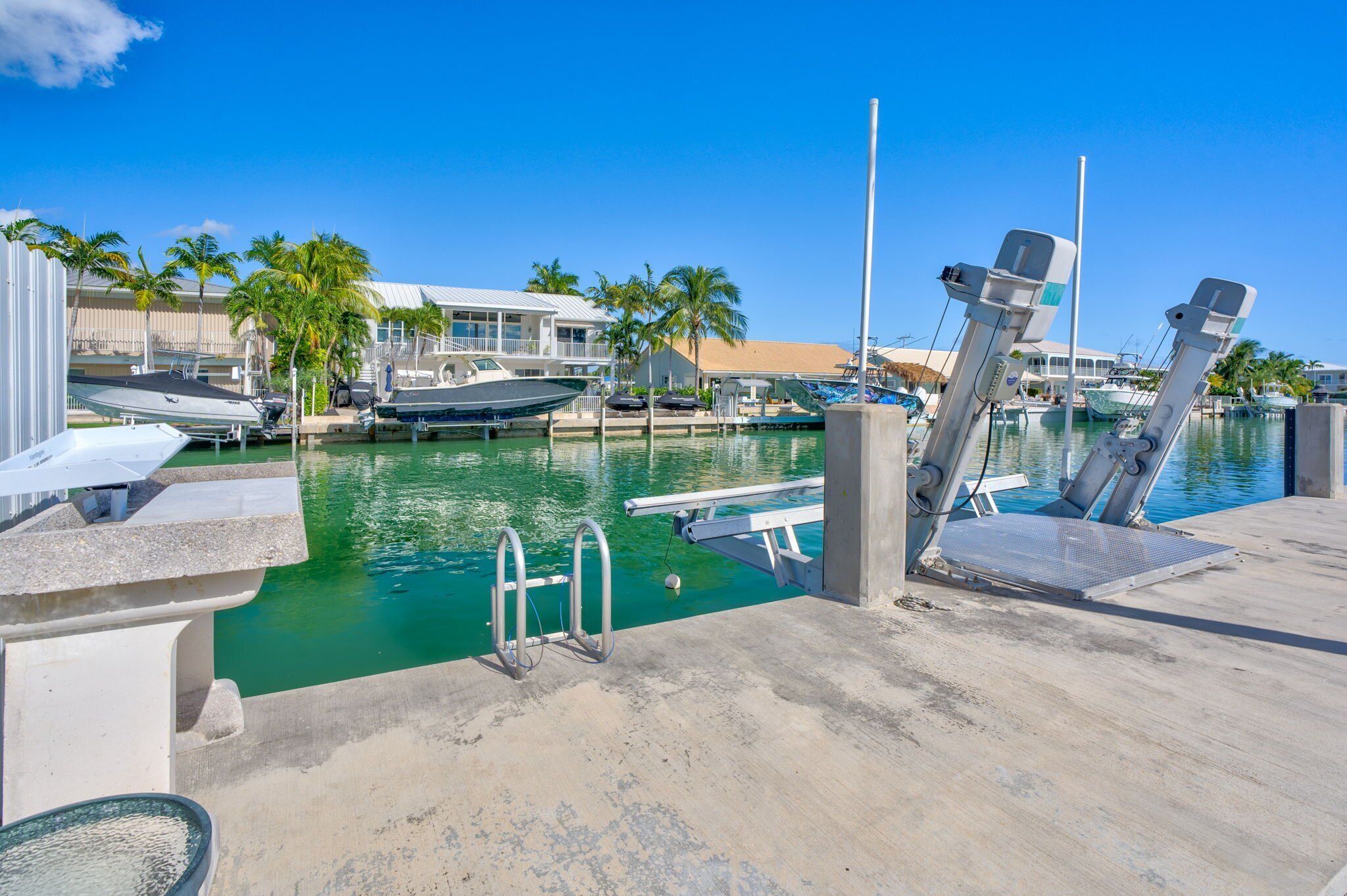 A marina with boats docked, a pool area, and a building with a sloped roof.