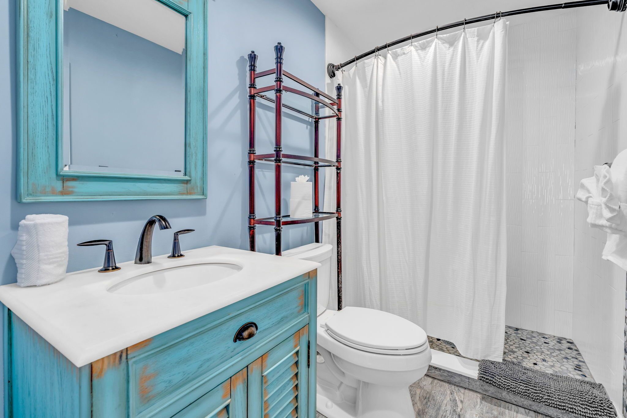A bathroom with a white sink, a mirror, a toilet, and a shower curtain.