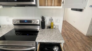 A kitchen with a built-in oven, microwave, and a drawer with utensils. - That cute house on Emerald! (Palm Bay)