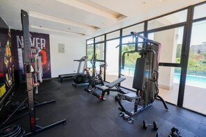 Ett gym med konditionsmaskiner, utrustning för styrketräning och en träningsbänk.