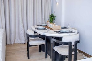 A dining area with a round table, four chairs, and a plant on the table. - 🌇 Fully Serviced 1-Bedroom Apartment at Riverbank, Two Rivers – Nairobi (Nairobi)