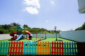 Ein Spielplatz mit Rutschen und Schaukeln, umgeben von einem bunten Zaun.