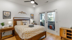 A bedroom with a bed, nightstands, a ceiling fan, and a sliding glass door leading to an outdoor area. - Bespoke Outpost: A stylish 3-bedroom retreat in scenic Chattanooga, TN. (Chattanooga)