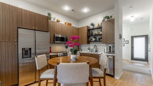 A modern kitchen with wooden cabinets, a stainless steel refrigerator, a microwave, and a dining table with chairs. - Bespoke Outpost: A stylish 3-bedroom retreat in scenic Chattanooga, TN. (Chattanooga)