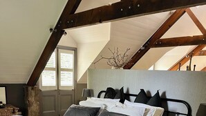 Une chambre à coucher avec un lit, des tables de chevet, une fenêtre et une vue sur l’extérieur.