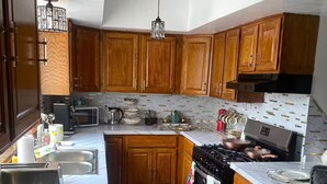 A kitchen with wooden cabinets, a stove, a microwave, and a sink. - Lorenzo Inn (Boston)