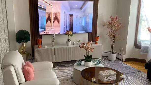 A modern living room with a flat-screen TV, a white sofa, a coffee table, and decorative items. - Lorenzo Inn (Boston)