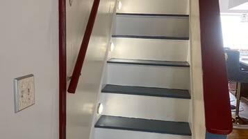 Eine Treppe mit weißen Stufen und roten Geländern, die zu einem Raum mit einer Chandelieber und Holzboden führt.