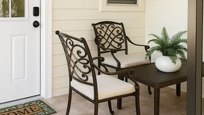 A porch with two chairs and a table, a door, and a window with blinds. - Superb studio with coastal comfort in Apollo Beach, Florida (Apollo Beach)