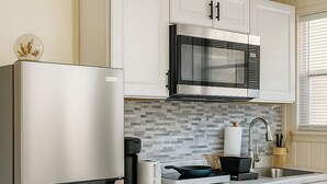 A modern kitchen with white cabinetry, stainless steel appliances, and a tiled backsplash. - Superb studio with coastal comfort in Apollo Beach, Florida (Apollo Beach)
