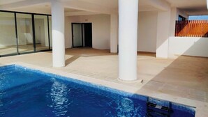 A modern indoor swimming pool with clear blue water, surrounded by white pillars and a tiled floor. - Joli Beach House - Third Floor T3 Apartment With Beautiful Views (Sal)
