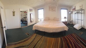 Une chambre à coucher avec un lit, une armoire, un miroir et une porte.