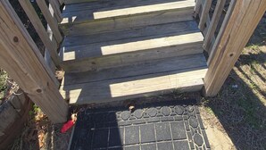Un escalier en bois mène à une porte dotée d’un panneau de verre, le tout étant entouré d’une terrasse en bois.
