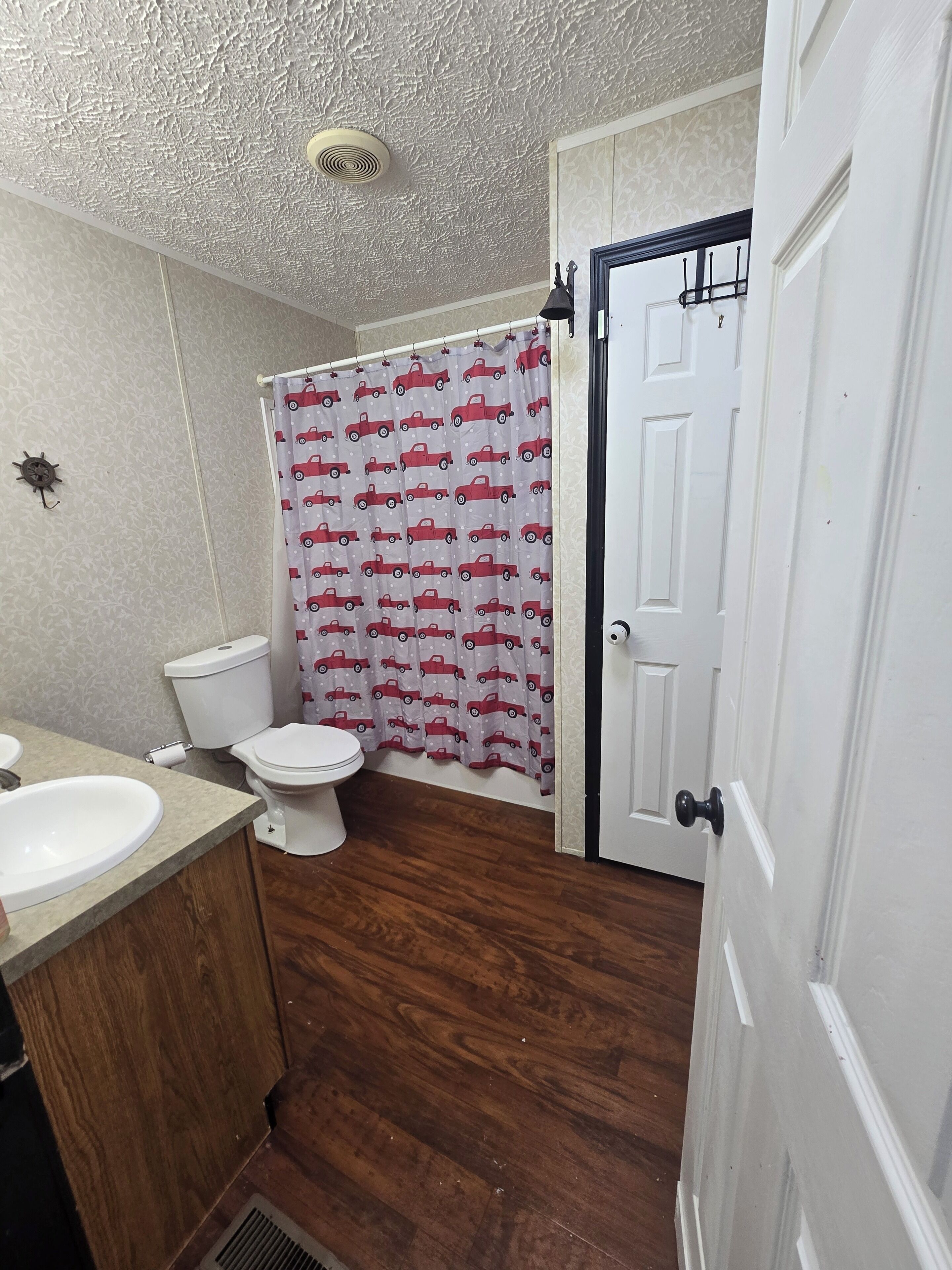 A bathroom with a toilet, sink, and shower curtain.