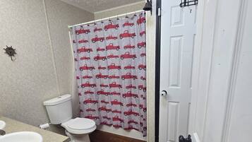 A bathroom with a toilet, sink, and shower curtain.