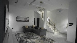 A modern living room with a sectional sofa, a patterned rug, and a staircase leading to another level.