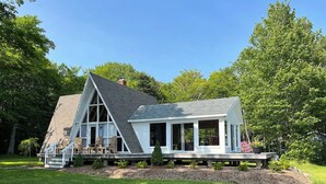 A two-story house with a large deck and a covered porch. - Lakeside A-frame Cottage (Clare)