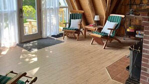 A cozy room with wooden beams, a fireplace, and two striped chairs. - Lakeside A-frame Cottage (Clare)