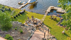 A lakeside patio with outdoor furniture, a fire pit, and a dock with a boat. - Pier Pressure by PMR, Lakefront, Private Boat Slip, fire pit, gameroom (Lake Harmony)