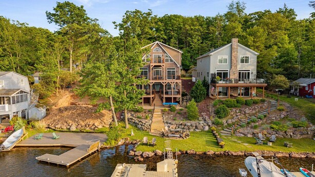 A lakeside property with a dock, a boat, and a house with a deck. - Pier Pressure by PMR, Lakefront, Private Boat Slip, fire pit, gameroom (Lake Harmony)