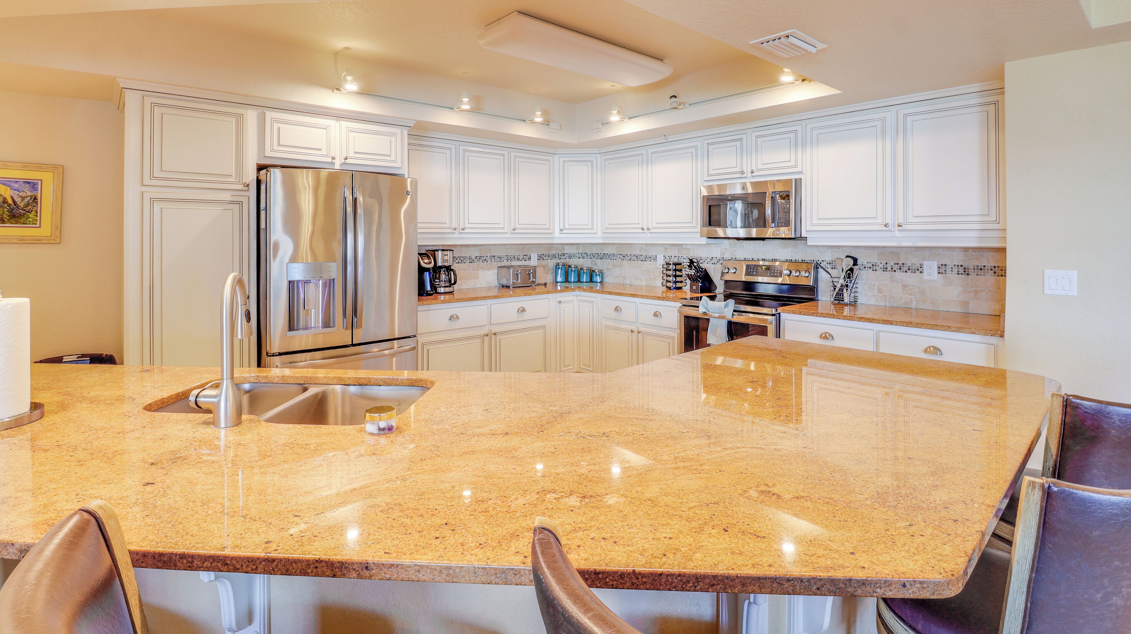 A modern kitchen with white cabinetry, stainless steel appliances, and a granite countertop.
