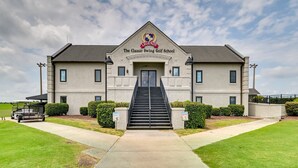 Het gebouw van The Classic Swing Golf School met een opvallende ingang en een heldere lucht.