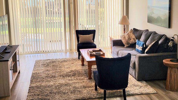 Een woonkamer met een bank, fauteuils, een salontafel en een televisie.