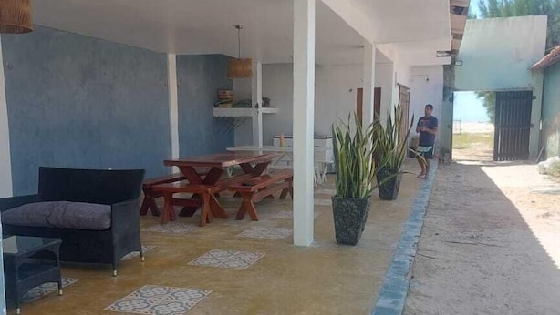 Un espace extérieur couvert, aménagé en patio, avec une table à manger, des chaises et un canapé.
