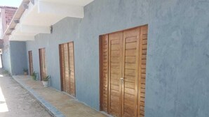 Une rangée de portes en bois, avec un mur bleu et un chemin pavé.