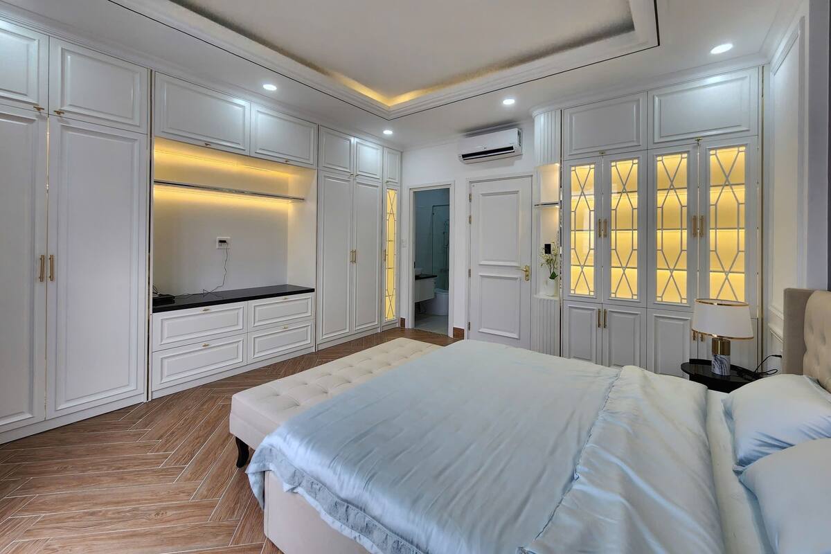 A bedroom with a large bed, built-in wardrobe, and a vanity with a mirror.