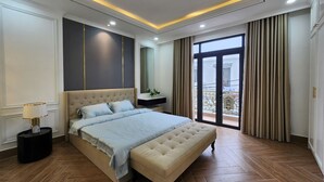 Une chambre moderne avec un grand lit, une table de chevet, un miroir et une vue sur le balcon extérieur.