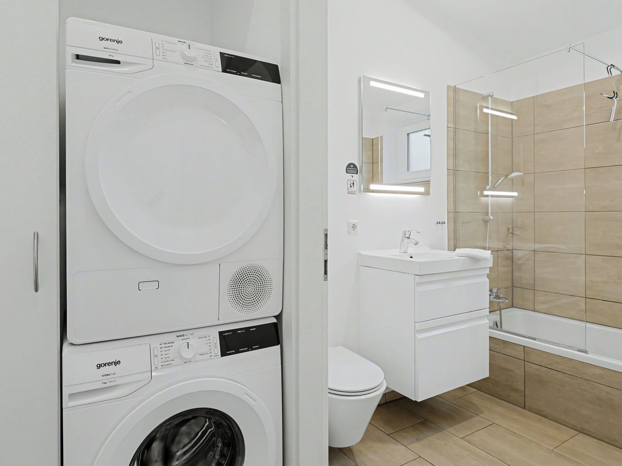 Un bagno moderno con lavatrice, WC, lavandino e doccia.