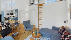 A spacious living area with a dining table, chairs, a sofa, and a staircase.
