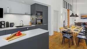 A modern kitchen with a central island, built-in appliances, and a dining area with a high table and chairs.