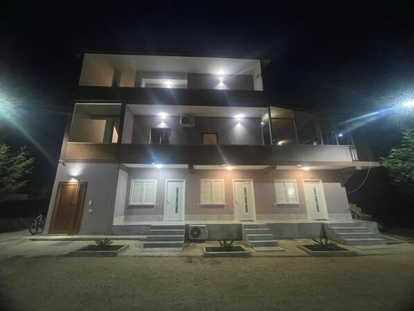 A multi-story building with a flat roof, multiple balconies, and a series of doors and windows. - Alessio Rooms Kruja (Fushe-Kruje)