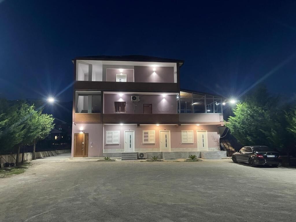 A multi-story building with a flat roof, large windows, and a covered outdoor area.