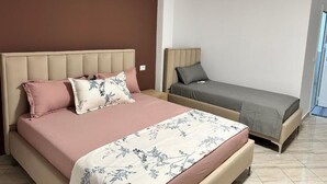 A bedroom with a large bed, a smaller bed, and a nightstand.