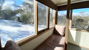 Quarto com uma janela grande, um banco de madeira e vista para uma paisagem nevada.