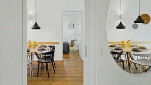 Uma área de jantar moderna com uma mesa redonda, cadeiras pretas e iluminação pendente.