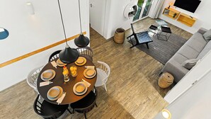 Ein modernes Wohnzimmer mit Essbereich, einem Flachbildfernseher und einer Glastür, die auf einen Balkon führt.