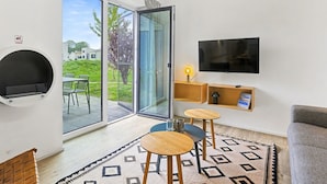 Un salon moderne doté d’un téléviseur, d’une cheminée, d’une porte vitrée donnant sur un balcon et d’un tapis à motifs.