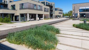 Uma rua urbana moderna com edifícios contemporâneos, área de estar ao ar livre e passarela para pedestres.