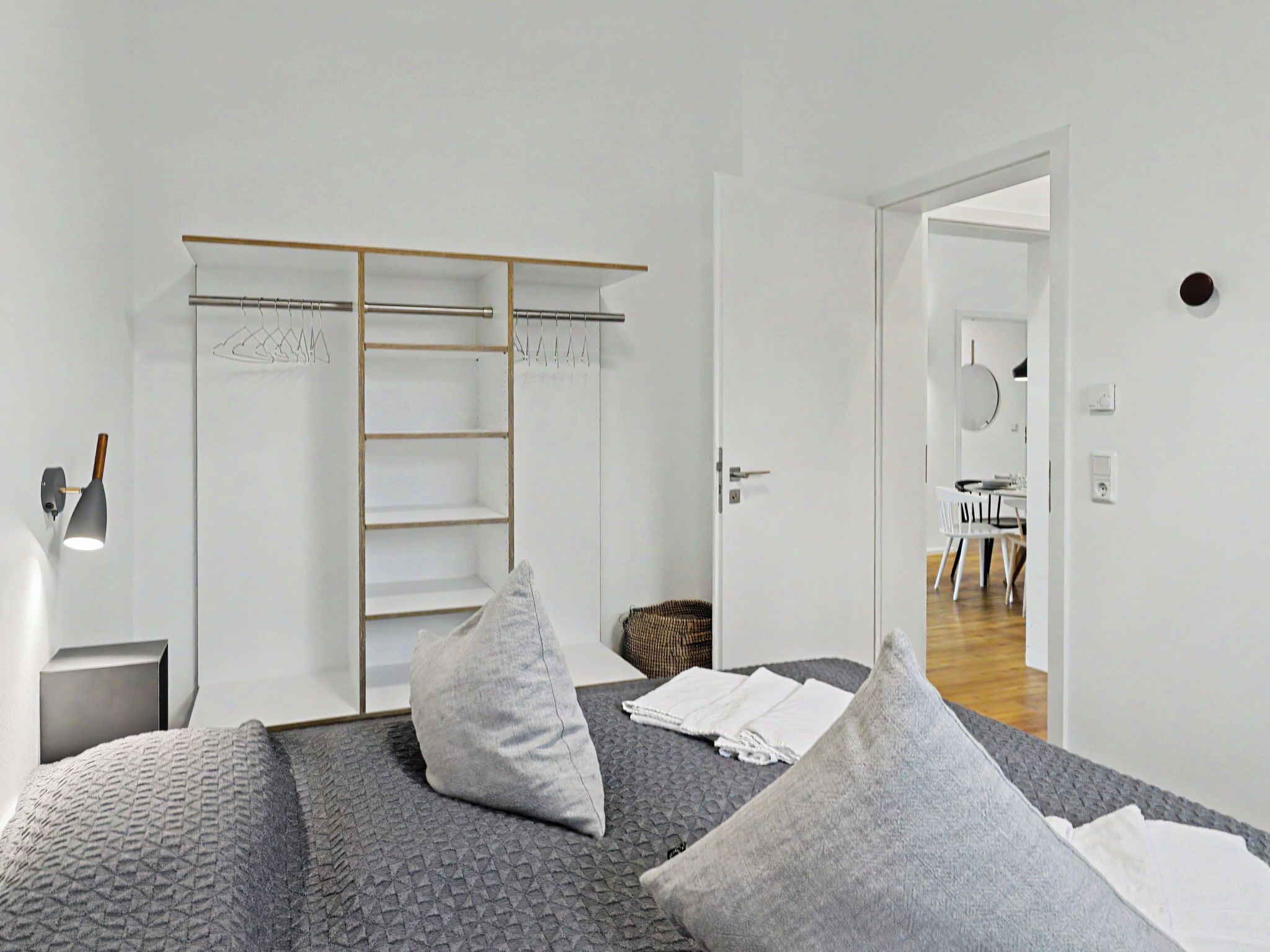 A bedroom with a bed, pillows, a wardrobe, and a bedside lamp.