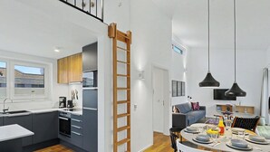 A modern kitchen with a built-in oven, a dining area with a round table, and a staircase leading to an upper level. - Dümmerliebe 271 by Interhome (Lembruch)